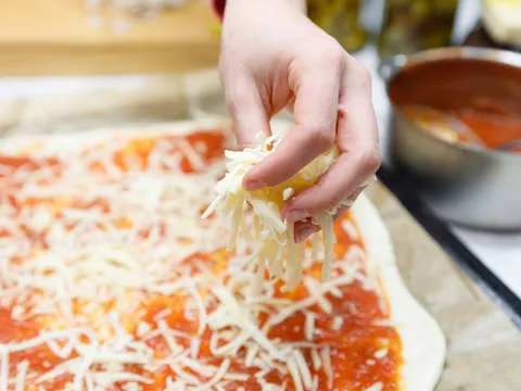 Stavljanje sira na pizzu